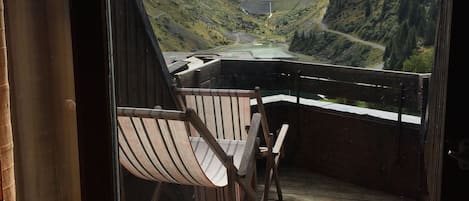 A wooden deck with a view of a valley and mountains.