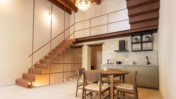 Een moderne keuken met een ingebouwde kookplaat, een spoelbak en een klein eethoekje met een tafel en stoelen.