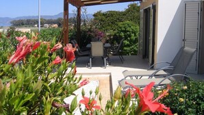 Un patio al aire libre con pérgola, zona de estar y vista al mar.