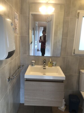 A bathroom with a white sink, a mirror, a hand dryer, and a toilet. - Peaceful Gite + PRIVATE Pool Exclusively for you +Magnificent Panoramic Views (Lalanne)