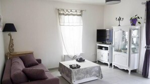 A living room with a sofa, a coffee table, a cabinet with glass doors, a television, and a lamp.