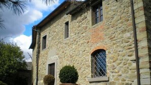 A stone building with a door and windows, a small garden area with potted plants, and a pathway leading to the entrance. - HillsideVilla overlooking the Tuscan landscape between Florence Arezzo and Siena (Loro Ciuffenna)