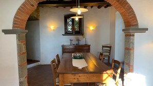 A dining area with a brick archway, wooden table, and chairs. - HillsideVilla overlooking the Tuscan landscape between Florence Arezzo and Siena (Loro Ciuffenna)