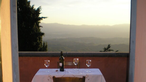 A table set for two with a bottle of wine and glasses, overlooking a mountainous landscape. - HillsideVilla overlooking the Tuscan landscape between Florence Arezzo and Siena (Loro Ciuffenna)