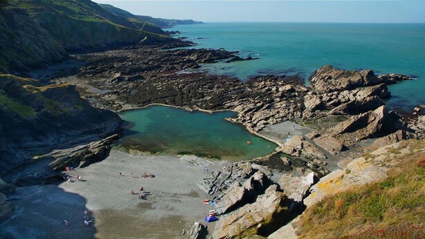 Una zona costera rocosa con una playa y agua cristalina.