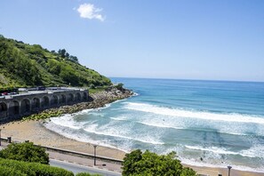 A coastal road with a stone bridge, a beach, and a forested hillside. - BEAUTIFUL BASQUE HOUSE WITH MAGNIFICENT VIEWS. (Getaria)