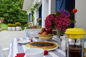 A table set outdoors with a pie, a bowl of fruit, and a vase of flowers. - BEAUTIFUL BASQUE HOUSE WITH MAGNIFICENT VIEWS. (Getaria)