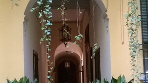 A building entrance with an arched doorway, potted plants on either side, and hanging vines. - The frog's hideaway - your palace in the city (CIN: IT037006C2NX87L3XB) (Bologna)