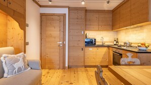 A compact kitchen with wooden cabinets, a dining table, and a sofa with a decorative pillow.