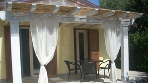 A covered outdoor seating area with a table and chairs, a pergola with white curtains, and a gravel ground. - Pretty Independent Villa free wi-fi 2 bicycles (Pietrasanta)