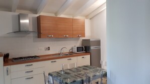 A compact kitchen with wooden cabinets, a stainless steel refrigerator, a microwave, and a dining table with chairs. - Pretty Independent Villa free wi-fi 2 bicycles (Pietrasanta)