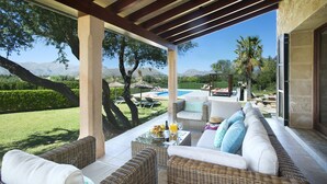 A covered outdoor seating area with wicker furniture, a pool, and a view of the mountains. - VILLA SIQUIER - LUXURY RETREAT WITH MOUNTAIN VIEWS (Pollensa)
