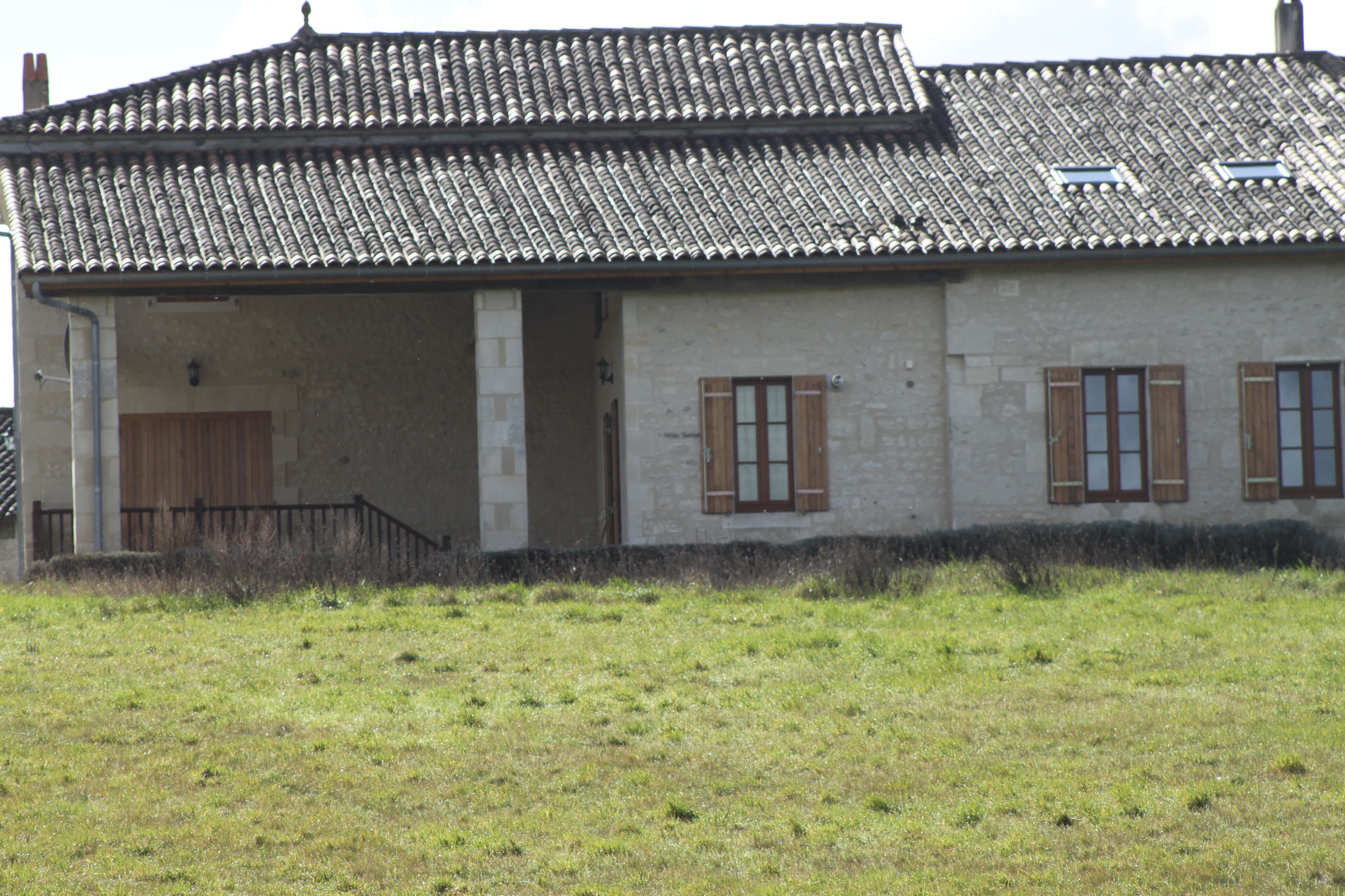 A two-story building with a tiled roof, a covered porch, and wooden shutters.