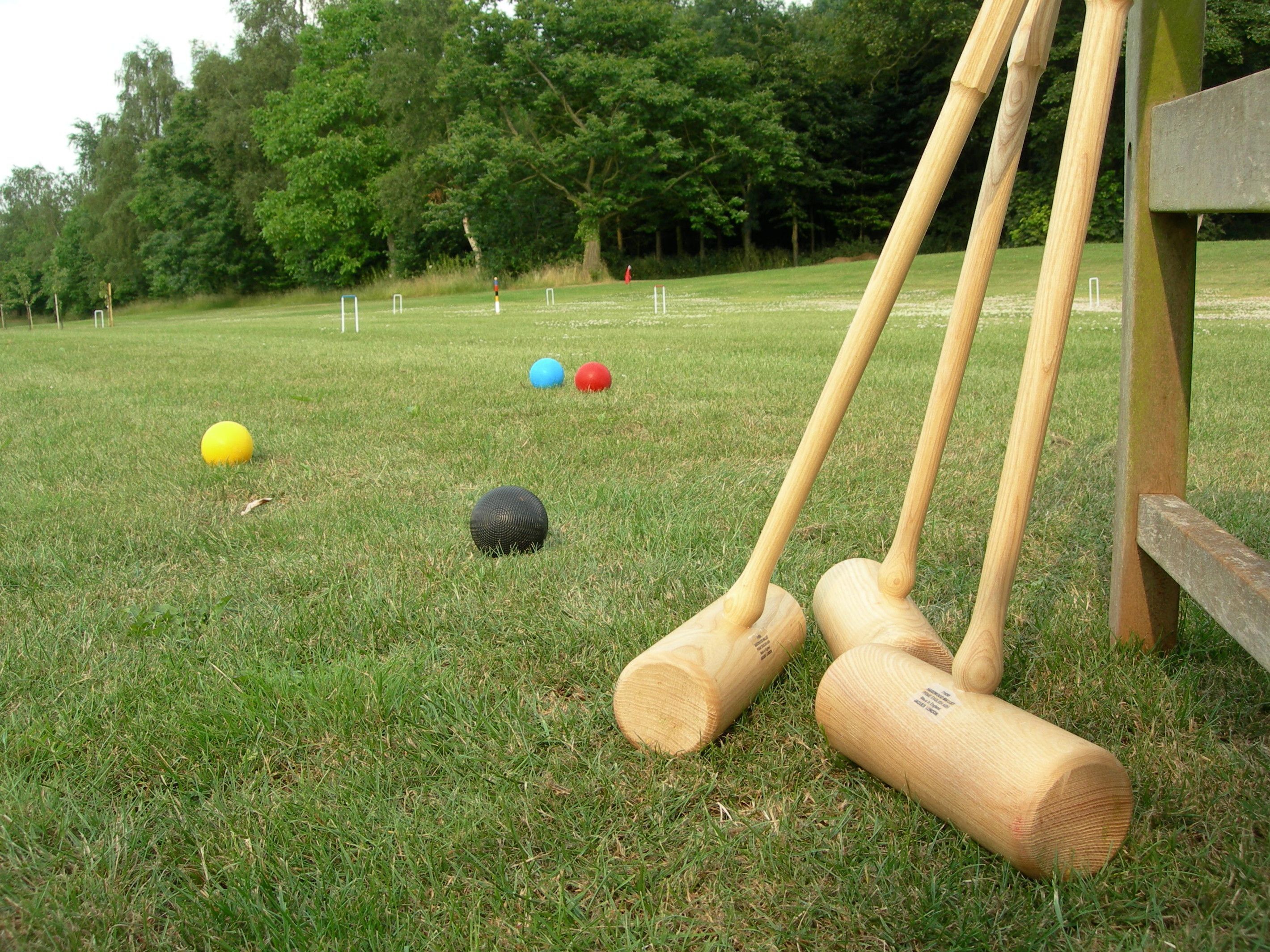 A croquet set on a grassy field with trees in the background.