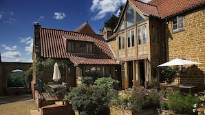 A stone building with a tiled roof, outdoor seating, and potted plants. - A spacious and luxurious retreat for couples near Great Tew (Chipping Norton)