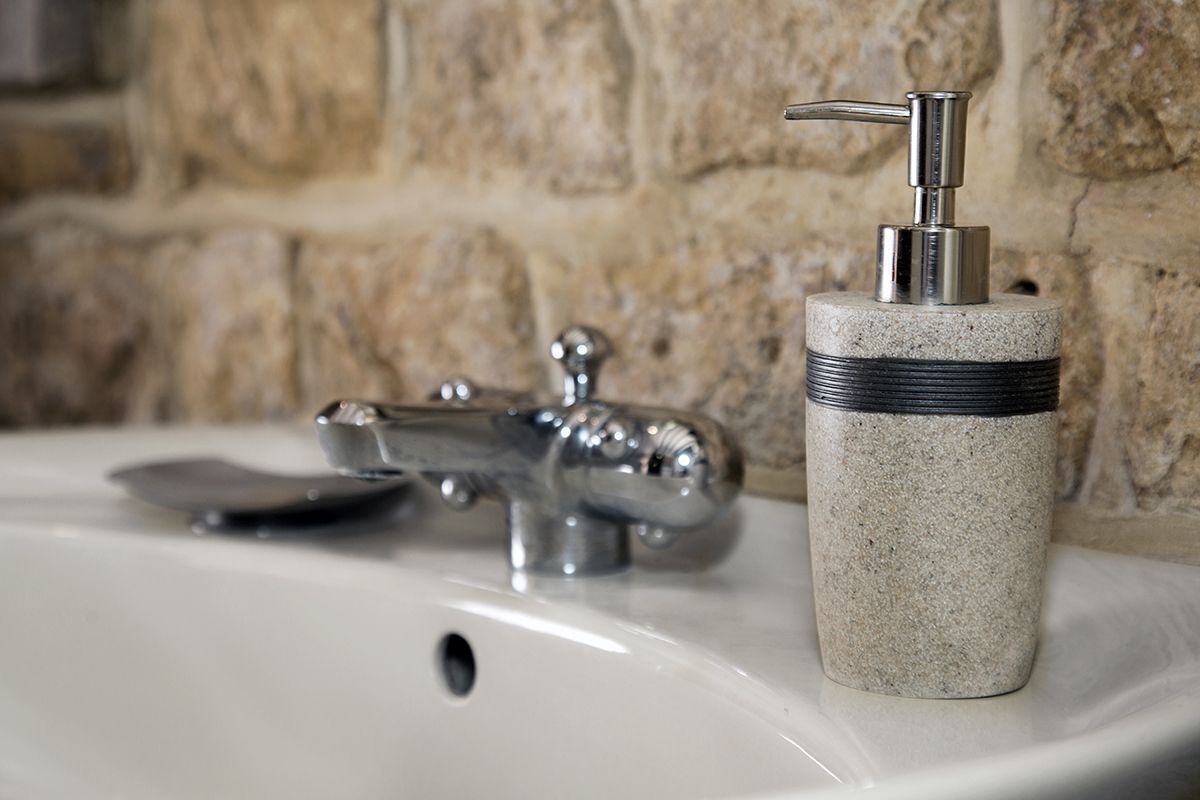 A bathroom sink with a modern faucet and a soap dispenser.