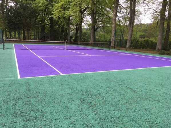 A tennis court with a net in the middle, surrounded by trees. - 2 bedroom pet friendly cottage sleeping 6 with sofa bed at The Highland Club (Loch Ness)
