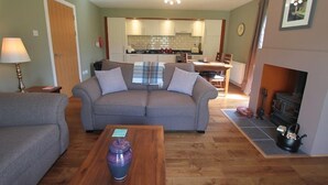 Ein Wohnzimmer mit einer Couch, einem Couchtisch, einem Kamin und einer Küche im Hintergrund.