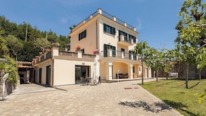 A two-story building with a balcony, a covered patio area, and a stone-paved courtyard. - Villa Yuri with private pool (Massa Lubrense)
