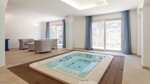 A spacious room with a large hot tub, a ceiling light, and a view of the outside through large windows. - Villa Yuri with private pool (Massa Lubrense)