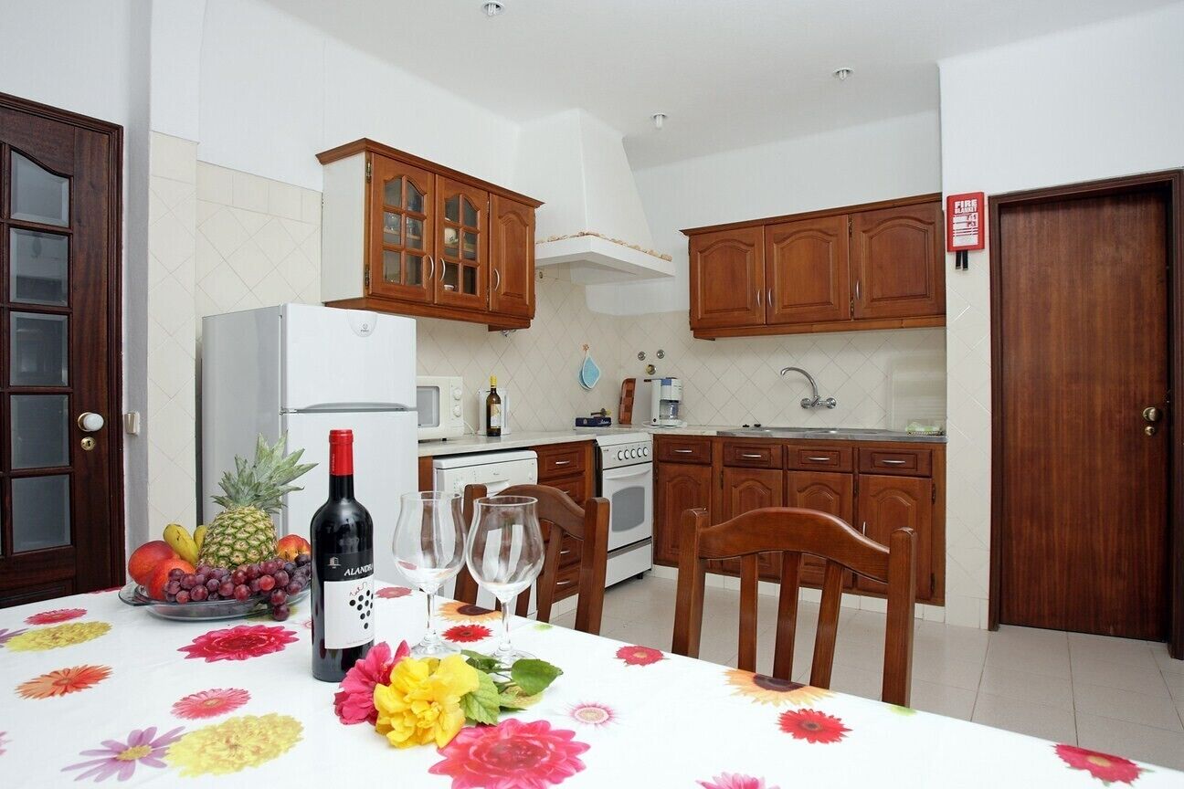 A kitchen with wooden cabinets, a refrigerator, a microwave, and a sink.