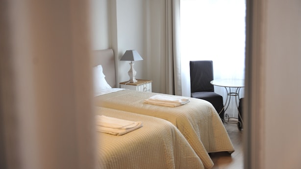 A hotel room with two beds, a small table, a chair, and a window with curtains. - 6 bedrooms, 3 bathrooms, 1 kitchen, 1 dining room, 5 minutes walk to the Vatican (Roma)