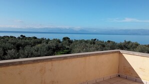 Ein Balkon mit Blick auf ein Gewässer und entfernte Berge.