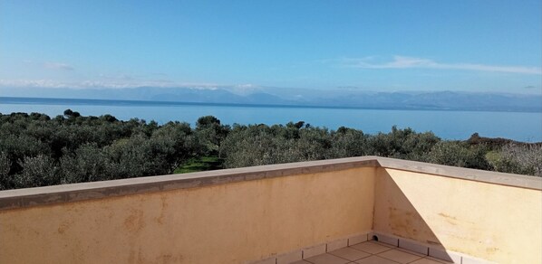 A balcony with a view of a body of water and distant mountains.