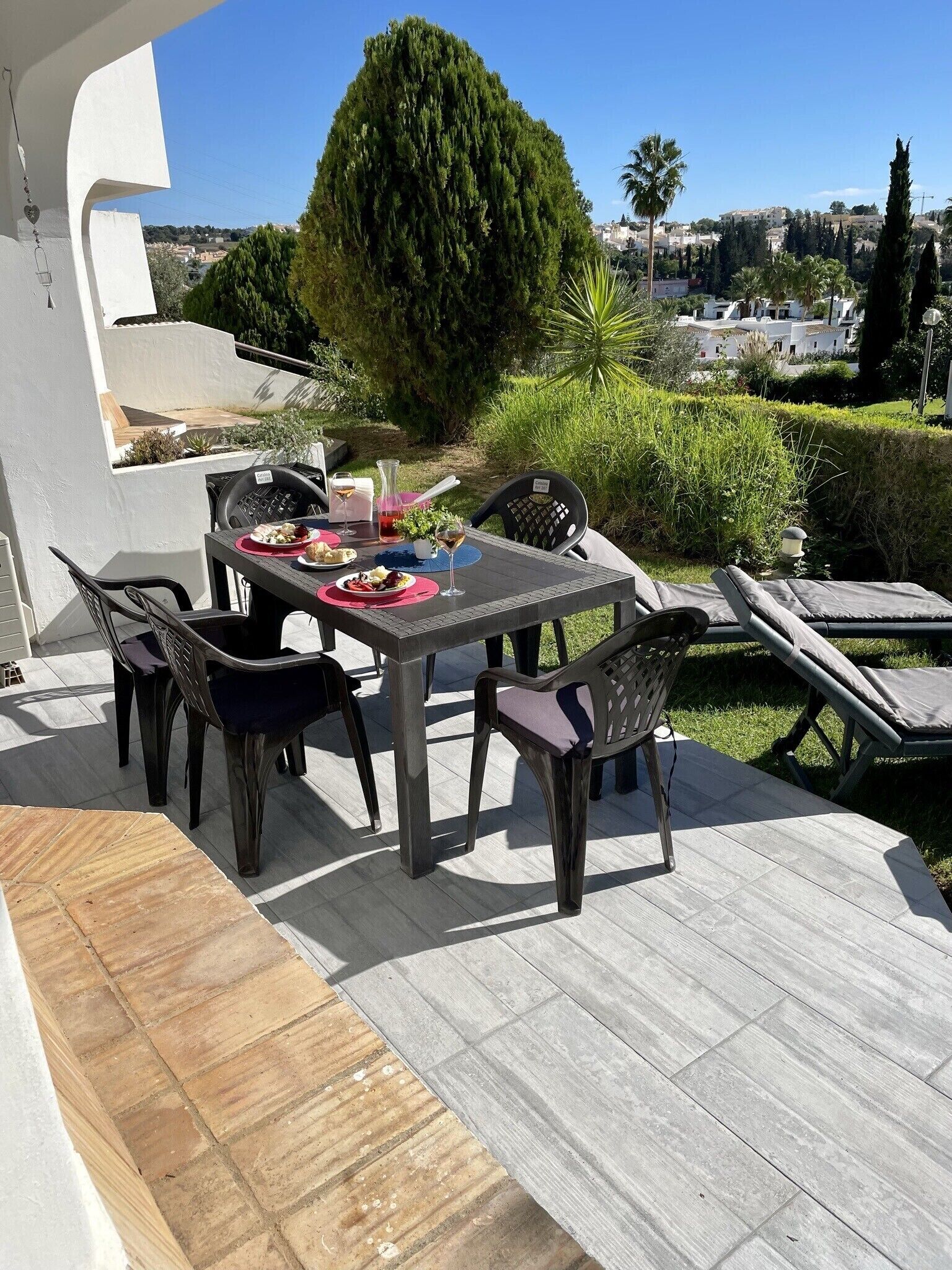 Eine Terrassengruppe im Freien mit Esstisch, Stühlen und einer Liege.