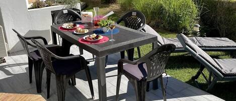 Eine Terrassengruppe im Freien mit Esstisch, Stühlen und einer Liege.