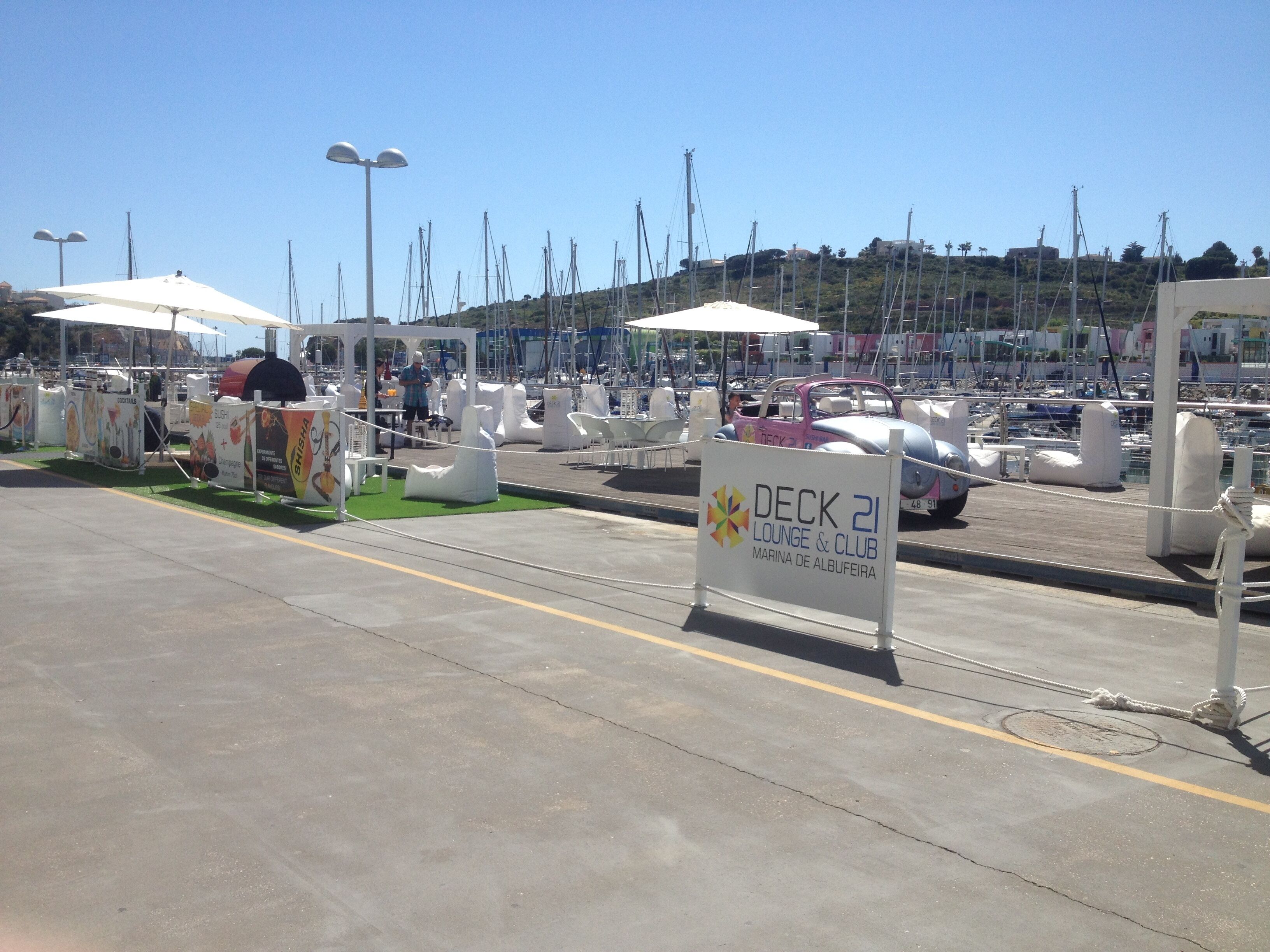 Un puerto deportivo con barcos, un área de descanso y un letrero que indica Deck 21 Lounge & Club.