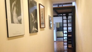 A hallway with framed artwork on the walls and a wooden floor. - Under the roof of Sofia (Florence)