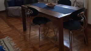 A dining area with a wooden table, four chairs, a bowl of fruit, and a sofa with cushions. - Under the roof of Sofia (Florence)