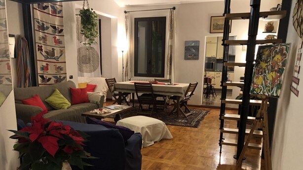 A cozy living room with a sofa, coffee table, and a dining area with chairs and a table. - Under the roof of Sofia (Florence)