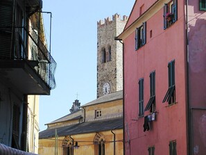 Une rue étroite bordée de bâtiments historiques, dont une tour abritant une horloge.