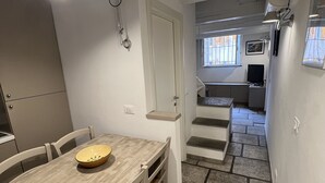 Cocina compacta con zona de comedor, una escalera que sube a un nivel superior y vistas al exterior a través de una ventana.