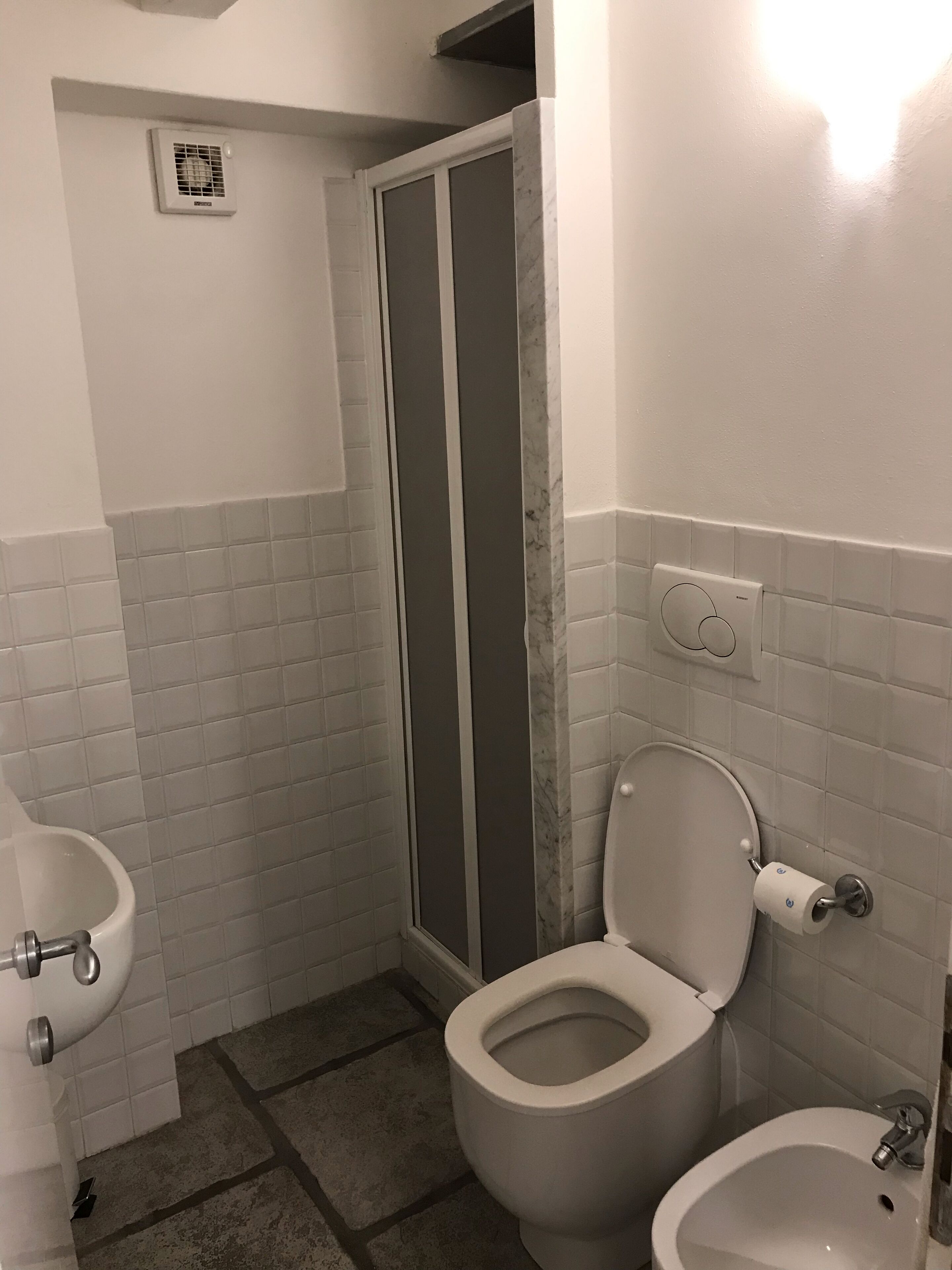 Een badkamer met toilet, bidet en douchecabine.