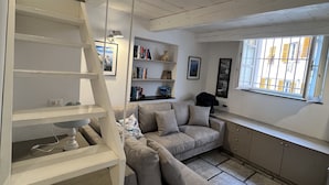 Una sala de estar moderna con una escalera empotrada, un sofá, un escritorio y una estantería.