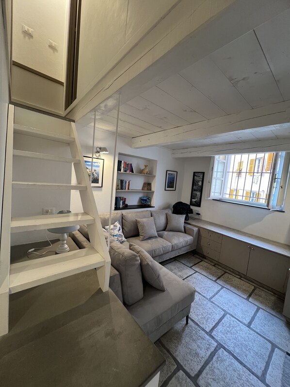 A modern living room with a built-in staircase, a sofa, a desk, and a bookshelf.