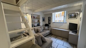 Una sala de estar moderna con una escalera, un sofá, un televisor y una estantería.
