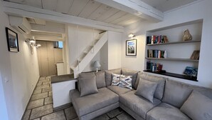 Una sala de estar moderna con un sofá modular gris, una escalera, una estantería y un cuadro en la pared.