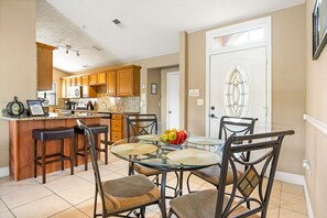 A kitchen with wooden cabinets, a microwave, and a glass island with stools. - Southeast Facing Private Pool,lakeside,3 Br-2 Bath,10 Min-disney, Modern (Kissimmee)