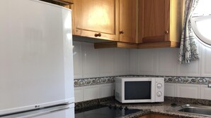 Una cocina con armarios de madera, un refrigerador blanco, un microondas y una encimera de granito.