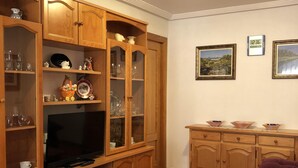 Una sala de estar con armarios de madera, un televisor, una mesa de centro y un sofá.