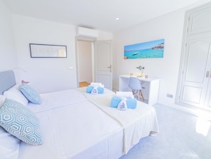 A bedroom with a large bed, a desk, and a painting of a beach scene. - Villa Alcanada Sunrise. Your villa with private pool and sea views in Alcanada. (Alcúdia)