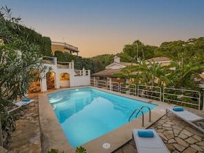 A swimming pool with a stone deck, surrounded by lounge chairs and a stone wall. - Villa Alcanada Sunrise. Your villa with private pool and sea views in Alcanada. (Alcúdia)