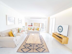 A modern living room with a sofa, coffee table, and a flat-screen TV. - Villa Alcanada Sunrise. Your villa with private pool and sea views in Alcanada. (Alcúdia)