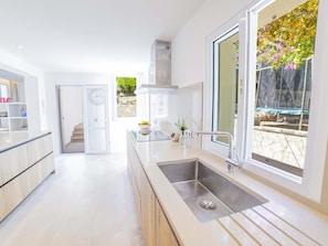 A modern kitchen with a large window, a built-in oven, and a sink. - Villa Alcanada Sunrise. Your villa with private pool and sea views in Alcanada. (Alcúdia)