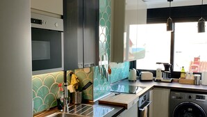Une cuisine moderne équipée d’un four encastré, d’un évier, d’un lave-linge et d’une fenêtre donnant sur l’extérieur.