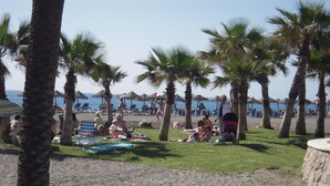 Une plage bordée de palmiers, avec des chaises longues et des parasols.